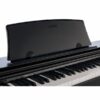 Piano numérique Casio noir avec couvercle de protection, vue rapprochée des touches blanches et noires.