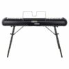 Piano numérique Korg noir sur trépied, vue avant, avec pupitre intégré pour partitions.