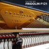 Vue rapprochée d’un piano droit neuf Fridolin F121 par Schimmel, montrant les cordes et les mécanismes internes en détail.