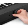 Main insérant une clé USB dans un clavier de piano numérique noir.