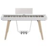 Piano numérique blanc sur pieds en bois avec pédale triple, parfait pour la pratique et les performances musicales.
