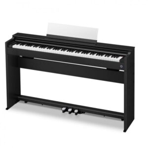 Un piano numérique noir avec 88 touches, trois pédales et un support de partition, est posé contre un fond blanc.